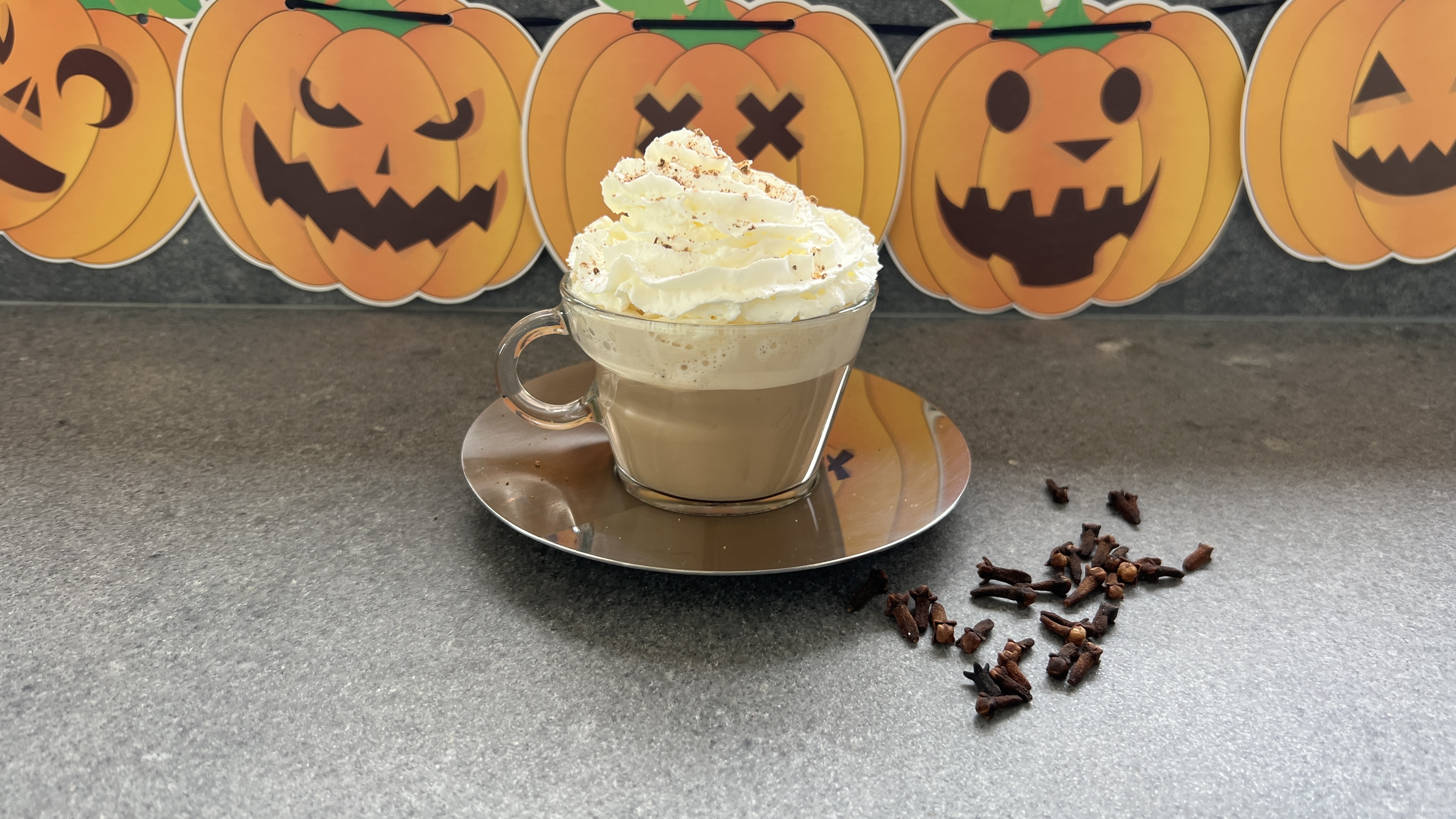 pumpkin pie latte with cream in front of Halloween decorations