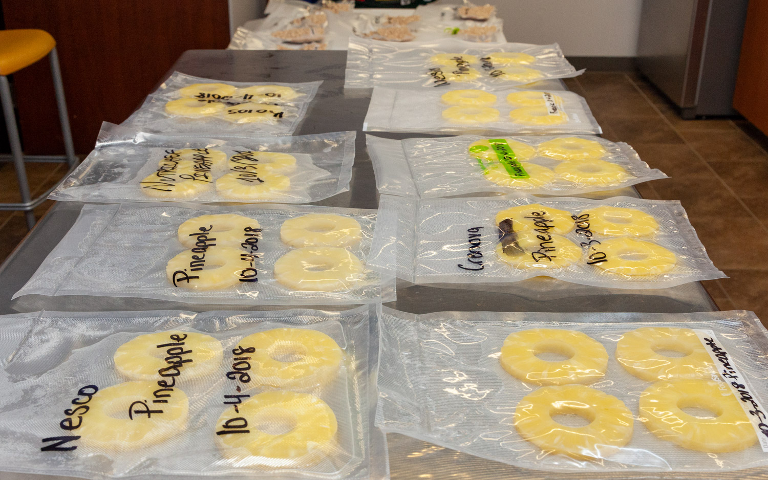 Best vacuum food sealers: an image showing pineapple rings placed into food saving machine bags ready for preserving