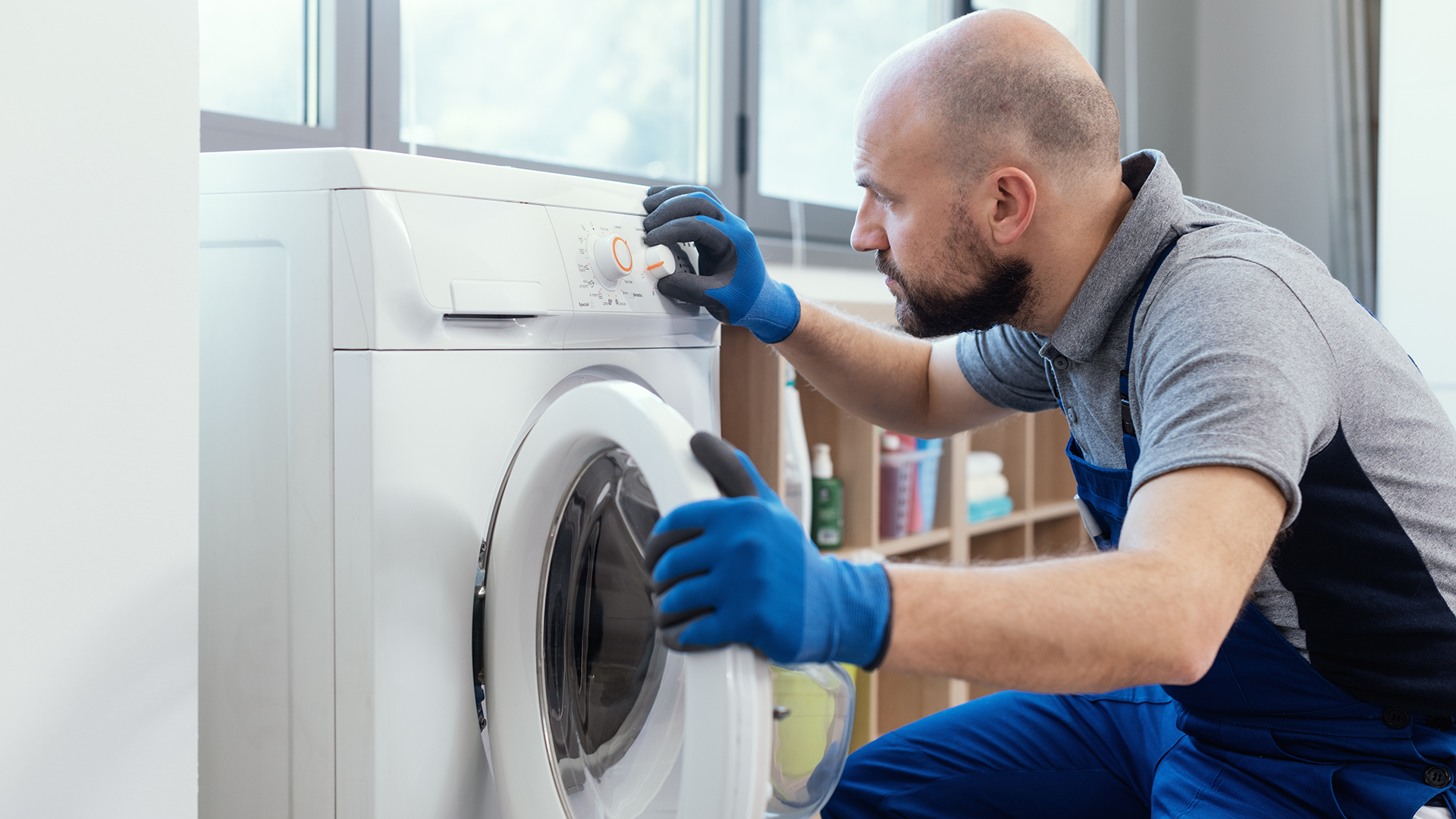 Man looking into a washing machine to repair it.